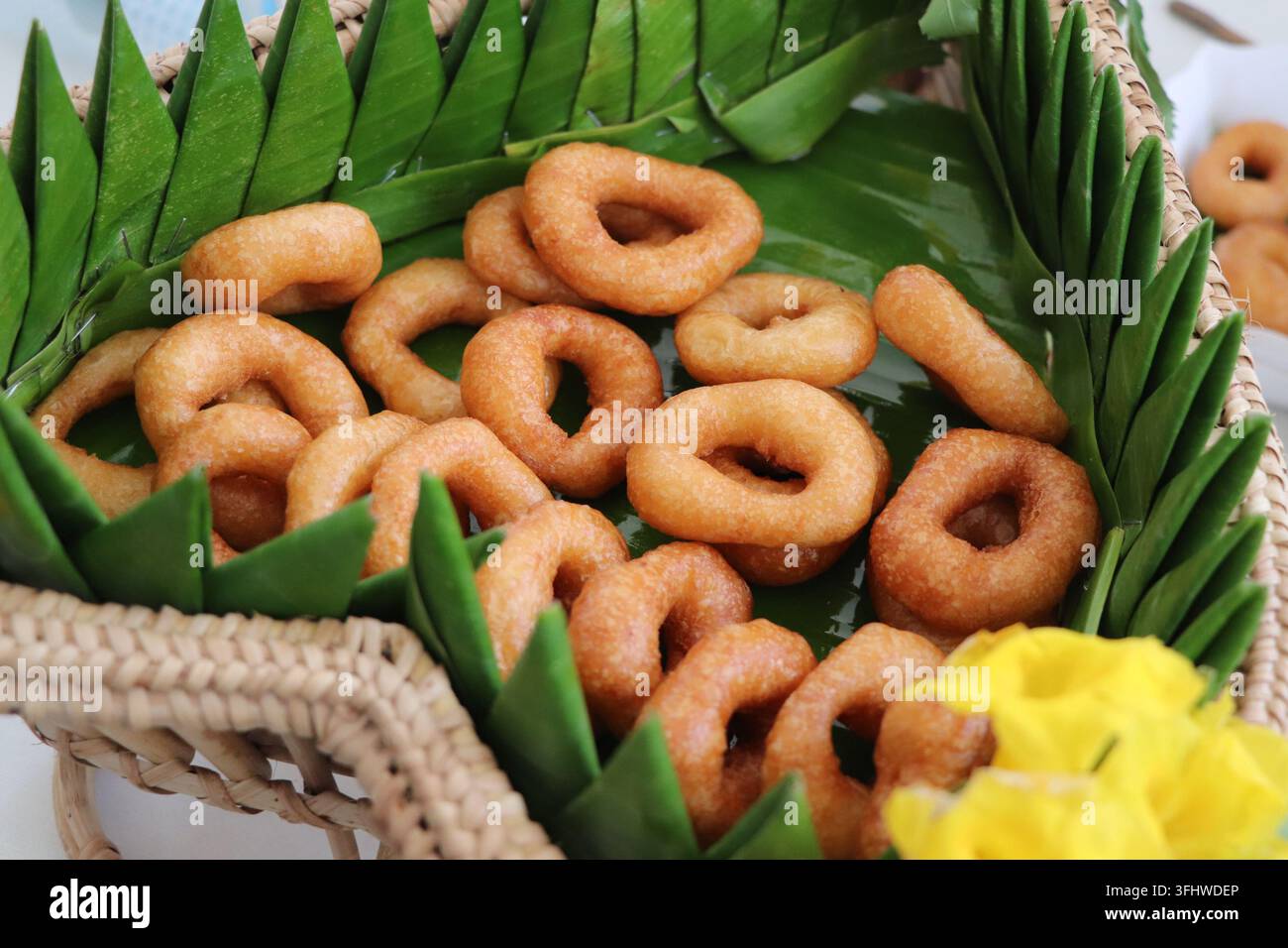 Traditionelle süße Ringdonuts, serviert in einem geflochtenen Korb, der mit Bananenblättern ausgelegt ist Stockfoto