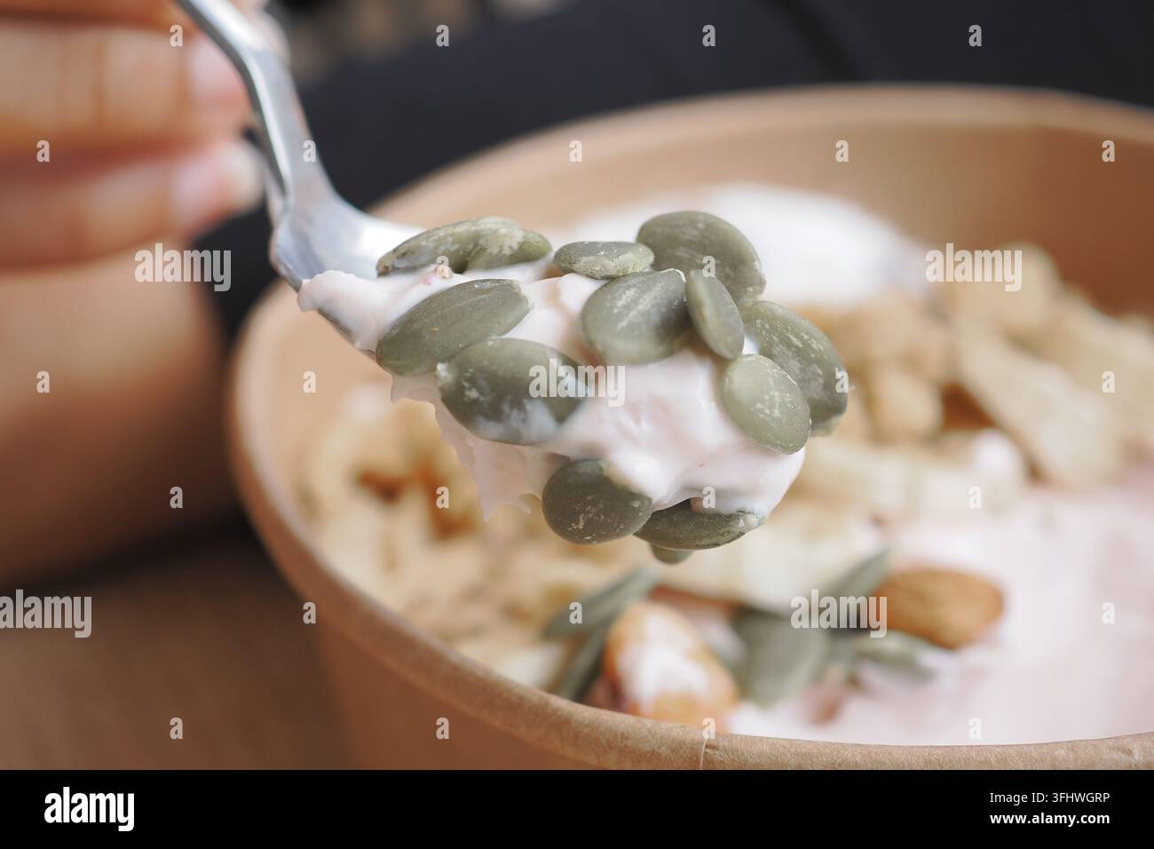 Joghurt mit Samen und Nüssen in einer Schüssel an einem Cafétisch essen Stockfoto