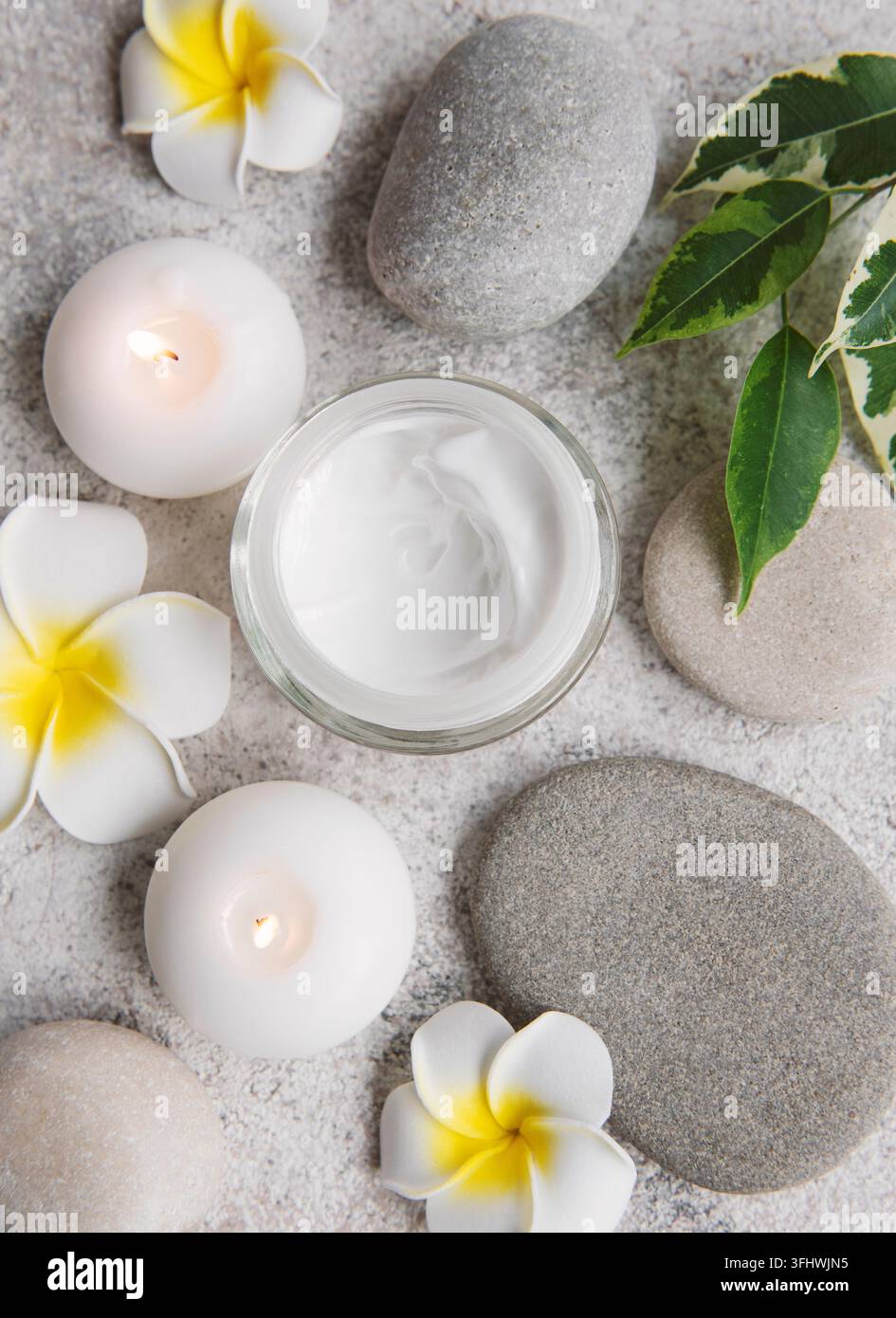 Spa-Behandlung mit Massagesteinen und feuchtigkeitsspendender Creme Stockfoto