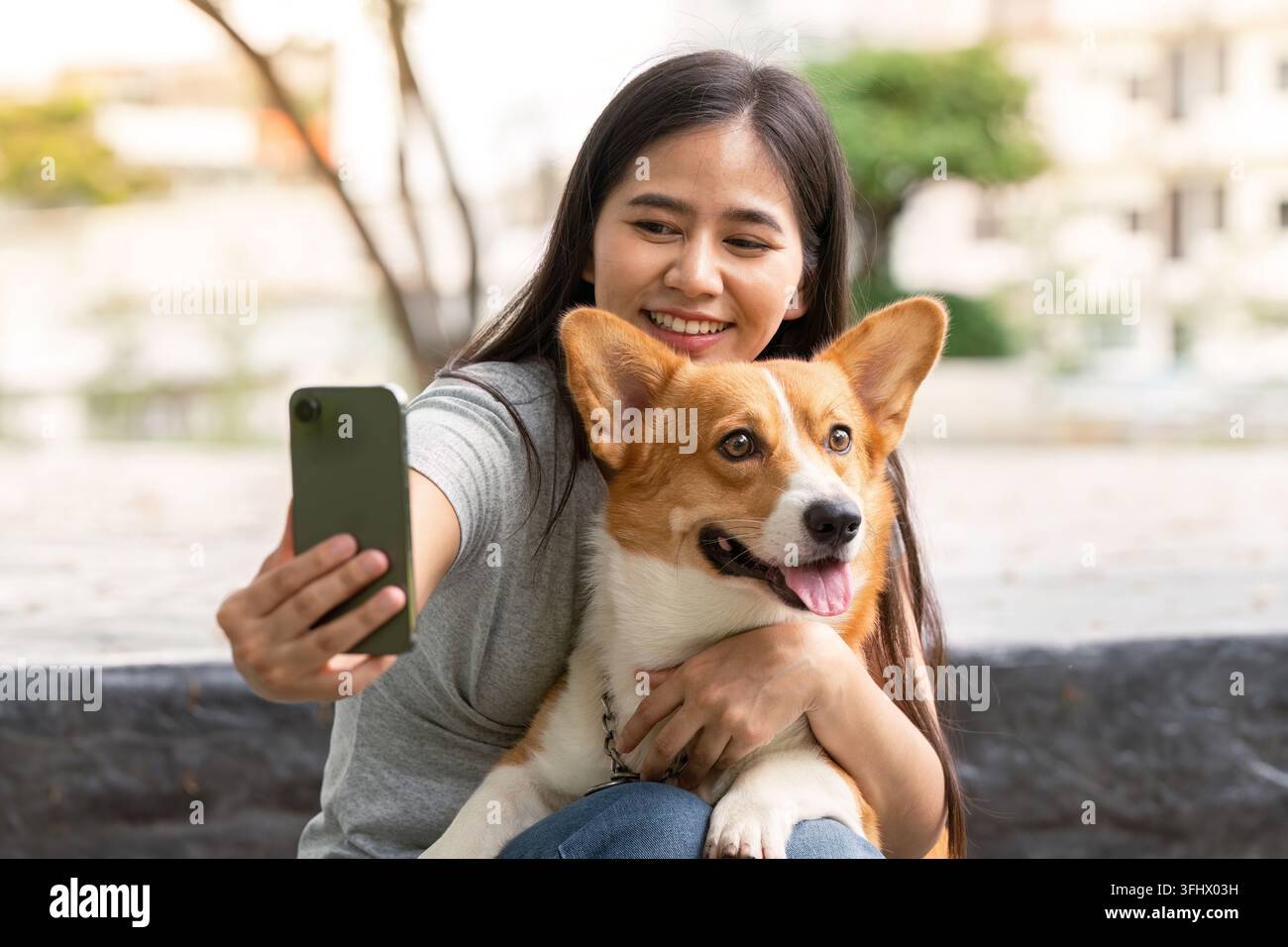 Selfie-Moment. Eine junge Frau macht ein Selfie mit ihrem Corgi im Park. Stockfoto
