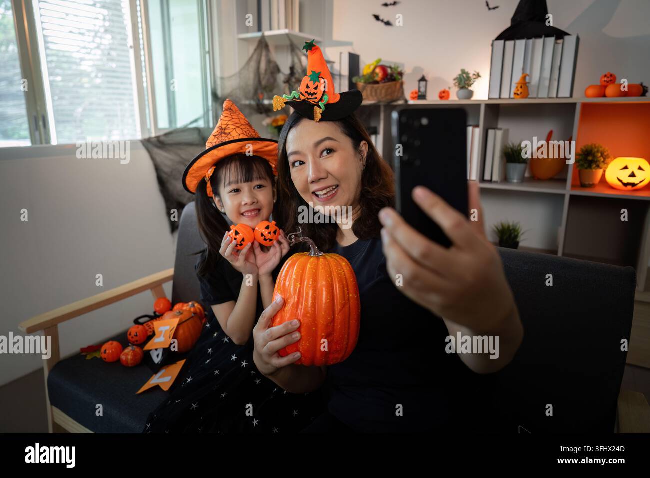 Halloween Selfie. Mutter und Tochter fangen fröhliche Momente mit Kürbissen ein. Stockfoto