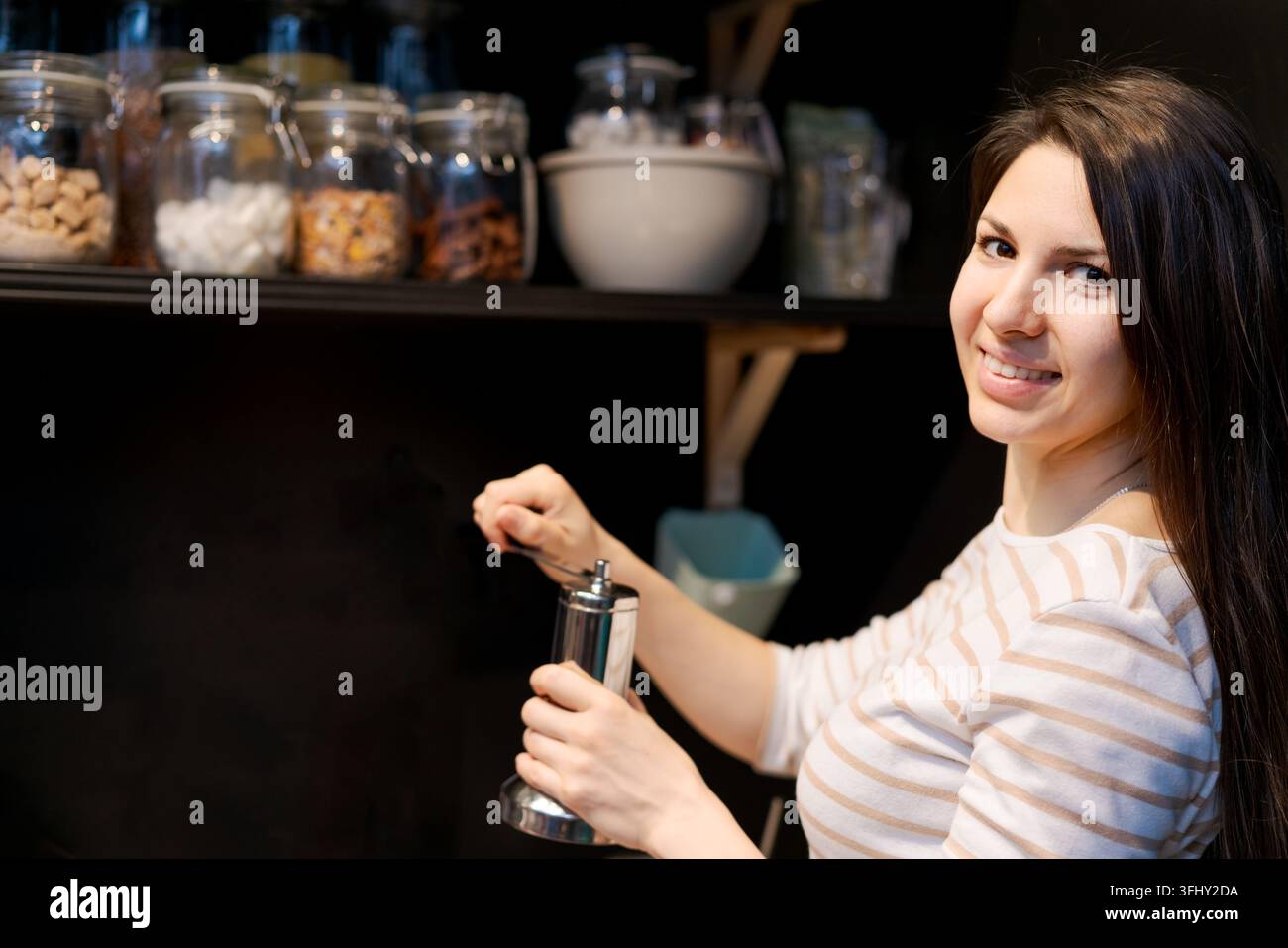 Eine Frau lächelt und hält einen Pfefferstreuer Stockfoto