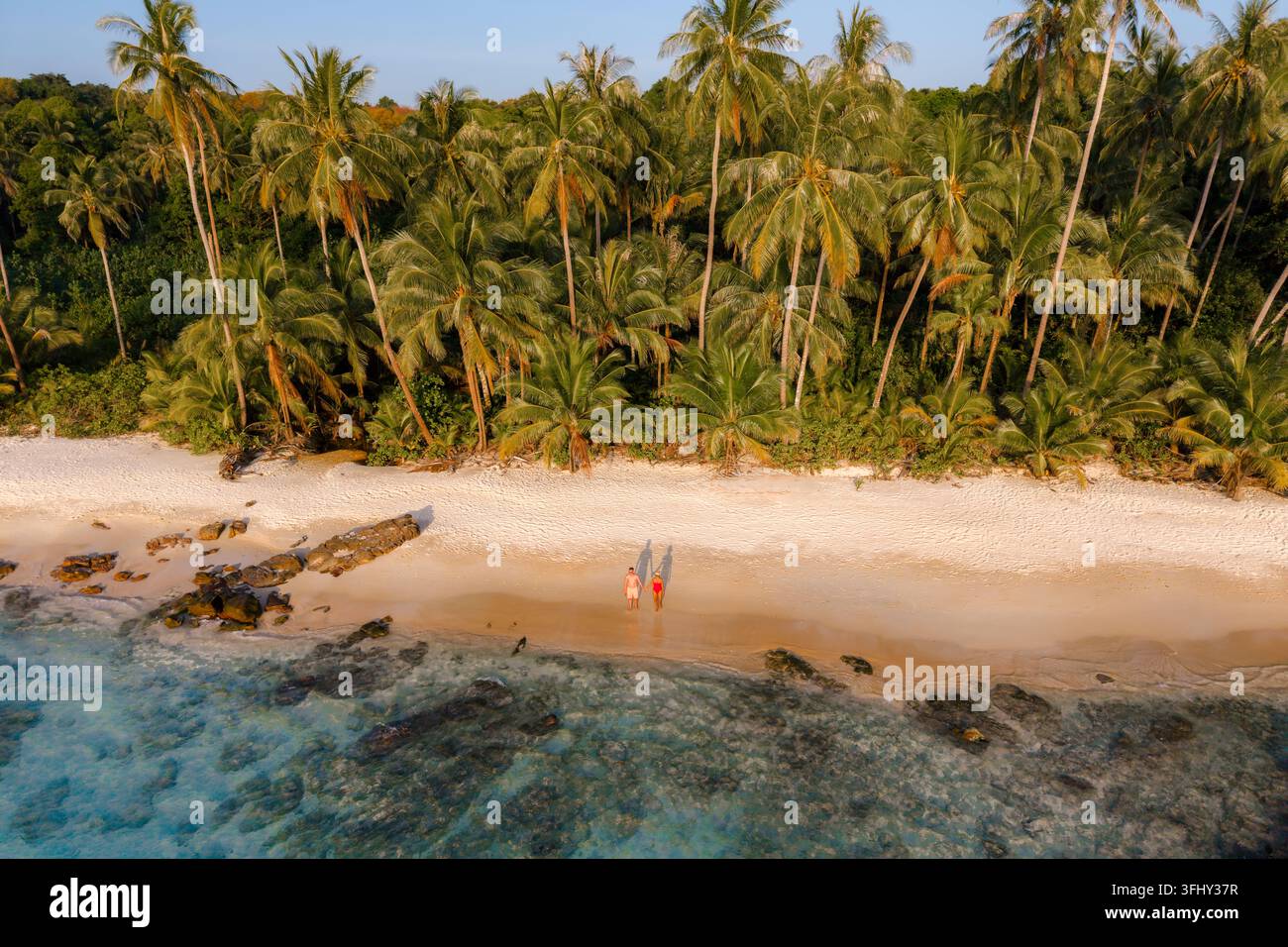 Schlendern Sie entlang der unberührten Küste des Takhian Beach auf Koh Kood Thailand, wo weicher weißer Sand auf kristallklares Wasser trifft. Palmen schwingen sanft im Th Stockfoto