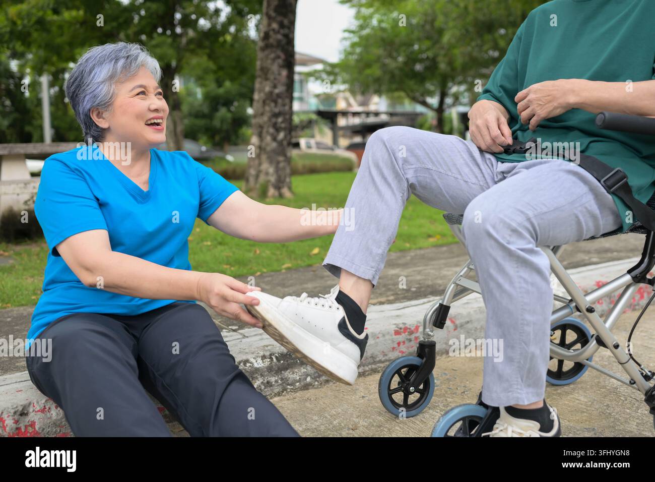 Seniorin spricht mit einem Mann im Rollstuhl in einem Park und schafft eine warme und unterstützende Atmosphäre Stockfoto