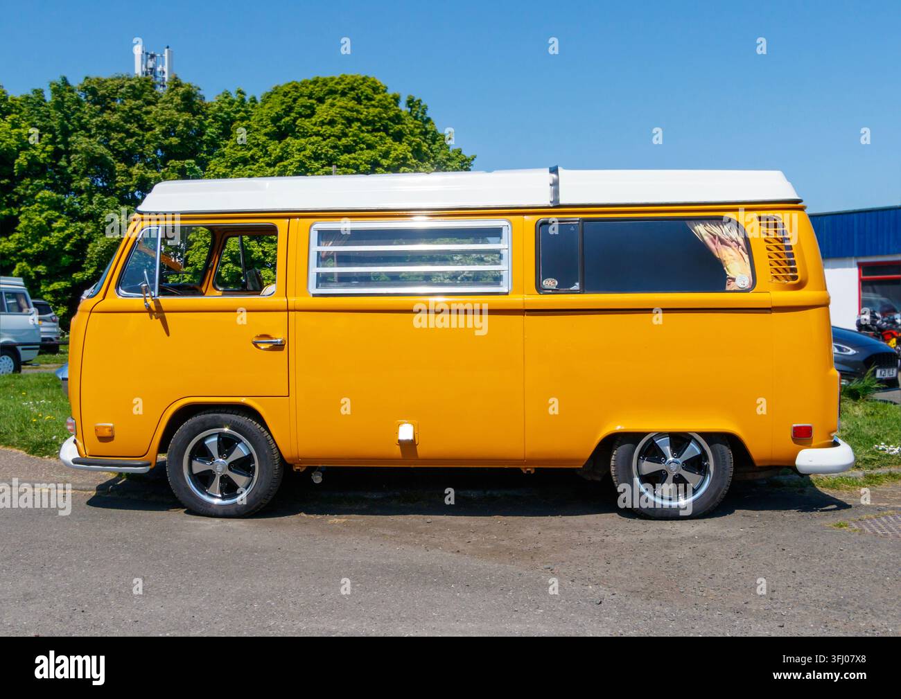 Gelber Volkswagen Typ 2 Wohnmobil, das draußen neben einem blauen Volkswagen-Van geparkt ist Stockfoto