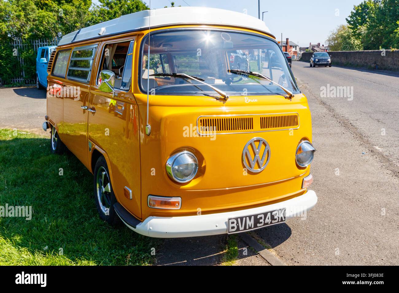 Gelber Volkswagen Typ 2 Wohnmobil, das draußen neben einem blauen Volkswagen-Van geparkt ist Stockfoto