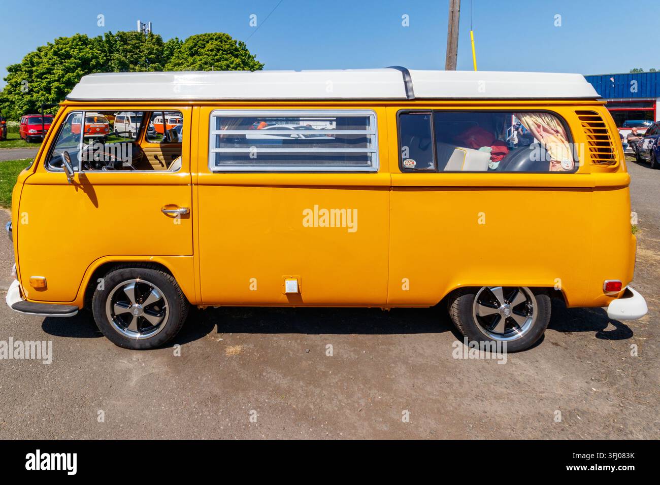 Gelber Volkswagen Typ 2 Wohnmobil, das draußen neben einem blauen Volkswagen-Van geparkt ist Stockfoto