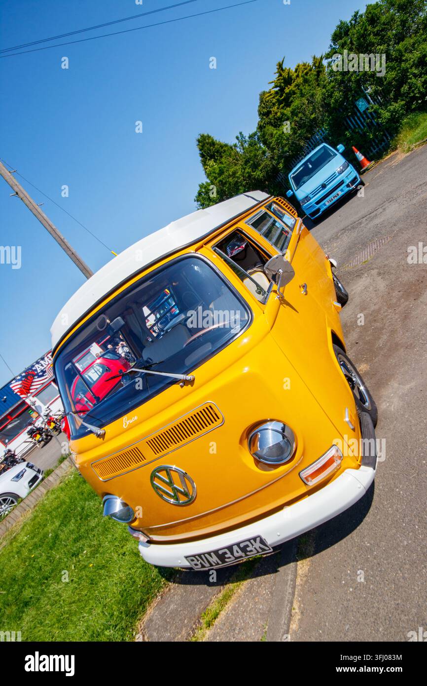 Gelber Volkswagen Typ 2 Wohnmobil, das draußen neben einem blauen Volkswagen-Van geparkt ist Stockfoto