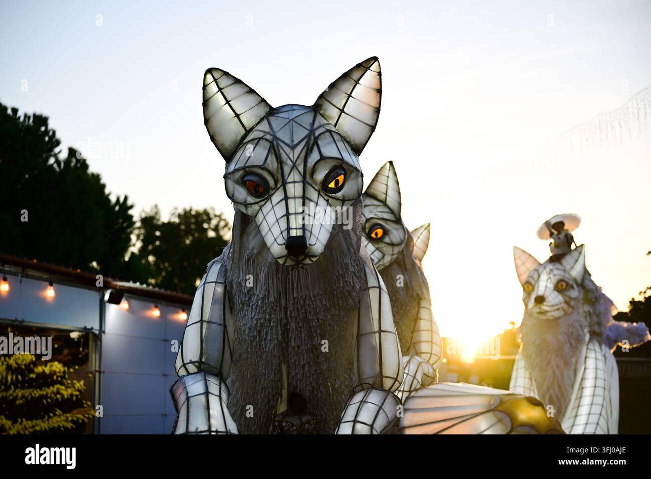 Rückseitig beleuchtete Fuchslaternen-Skulpturen bei Sonnenuntergang, leuchtende Augen und durchscheinende Paneele in einer Outdoor-Festival-Kunstinstallation Stockfoto