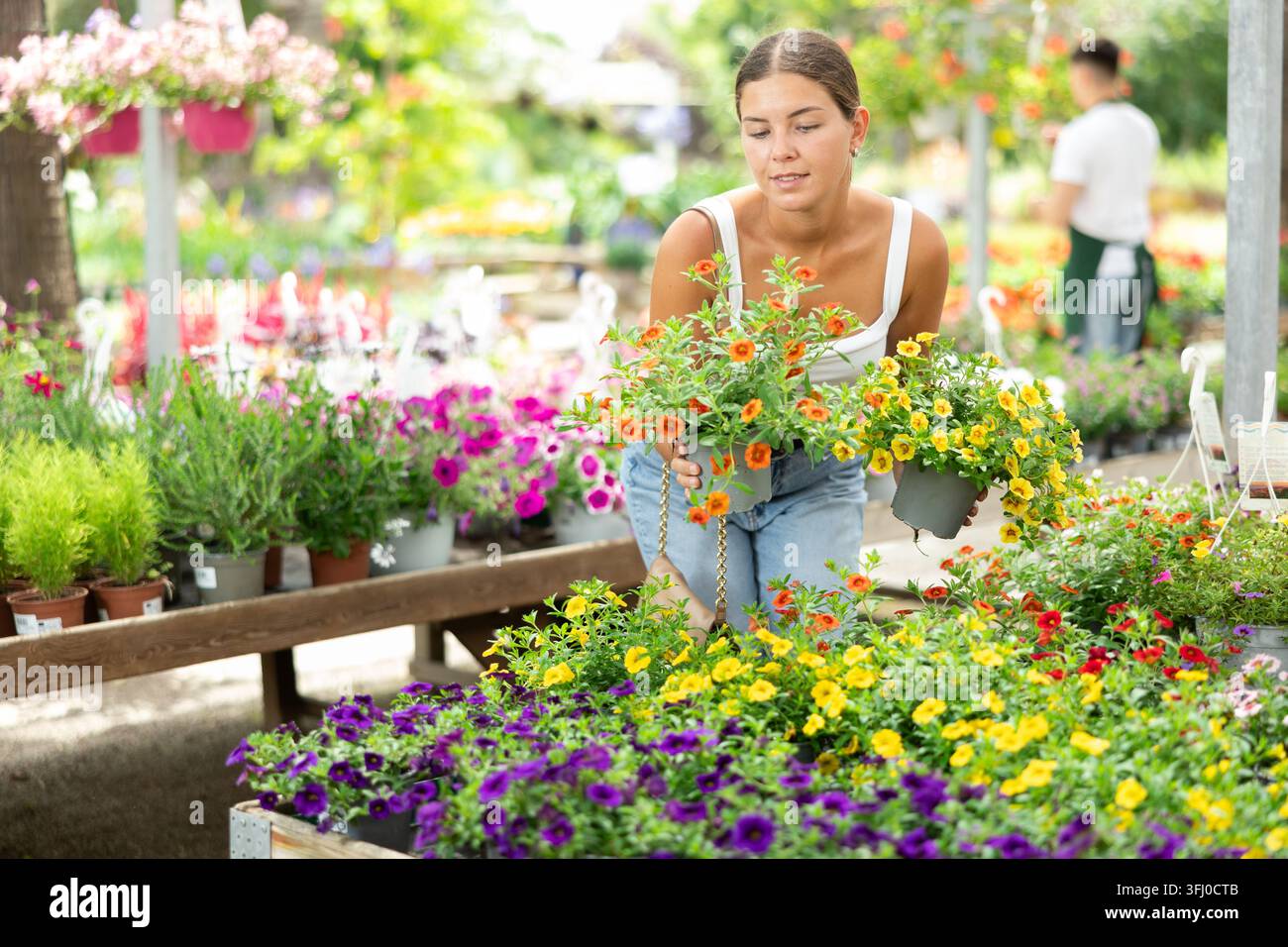 Aufmerksames Mädchen wählt Topfpflanzen Calibrachoa (Millionenglocken) auf einem Blumenverkauf auf dem Blumenmarkt Stockfoto