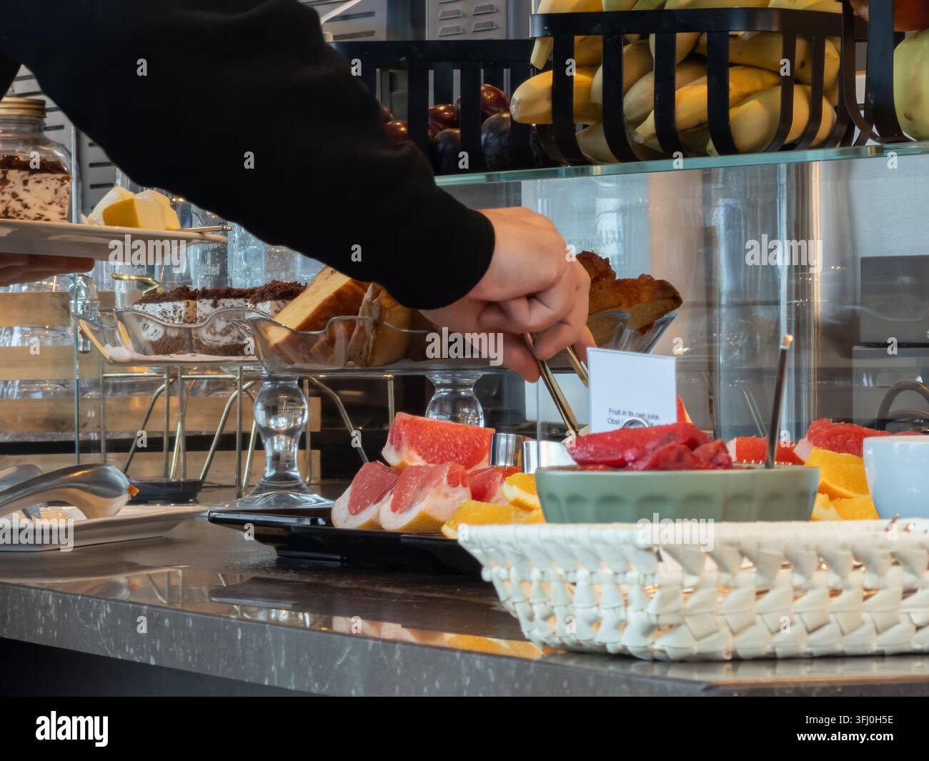 Eine Person pflückt gesundes Obst bei einem gekochten kontinentalen Frühstück, das eine Premium-Hotel-Gastgewerbedienstleistung mit einer Vielfalt an Nutri hervorhebt Stockfoto