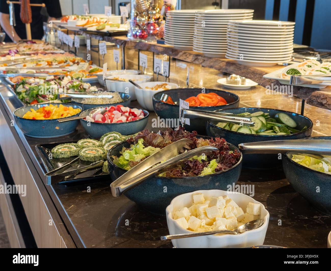 Ein üppiges Angebot an gesunden Salatalternativen, serviert in eleganten Keramikschüsseln auf einer modernen Marmorarbeitsplatte, bietet einen erstklassigen Catering-Service für Gäste Stockfoto