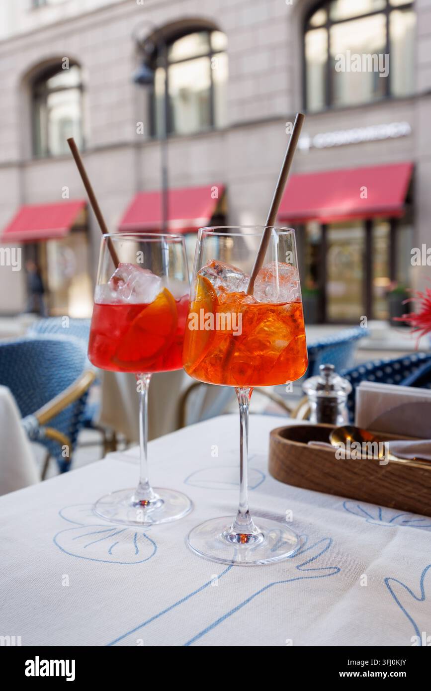 Moskau, Russland – 17. September 2026: Zwei orange-rote gekühlte Getränke in Stielgläsern stehen auf einer Tischdecke mit blauen Liniendrawings in einem Straßencafé. Stockfoto