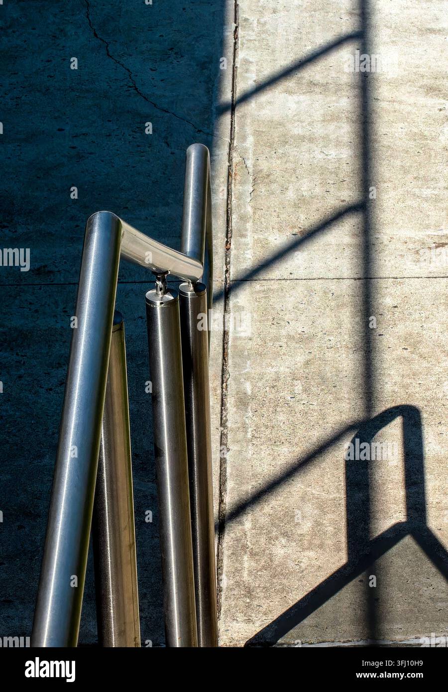 Ein modernes, gebürstetes Metallgeländer mit vertikalen Pfosten, das neben einer Betonfläche installiert ist Stockfoto