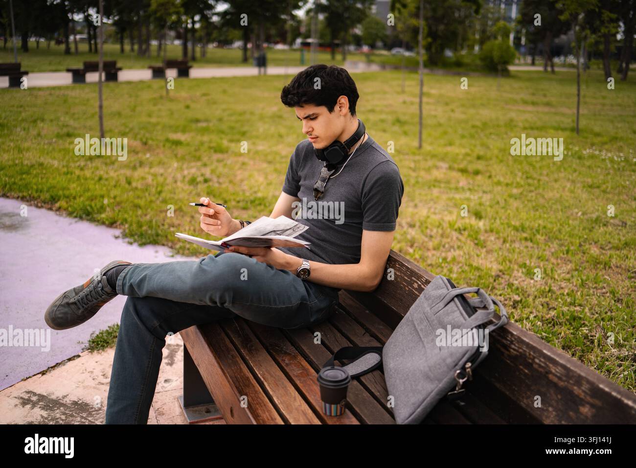 Junger erwachsener Student studiert im Park mit einem Buch im Freien Stockfoto
