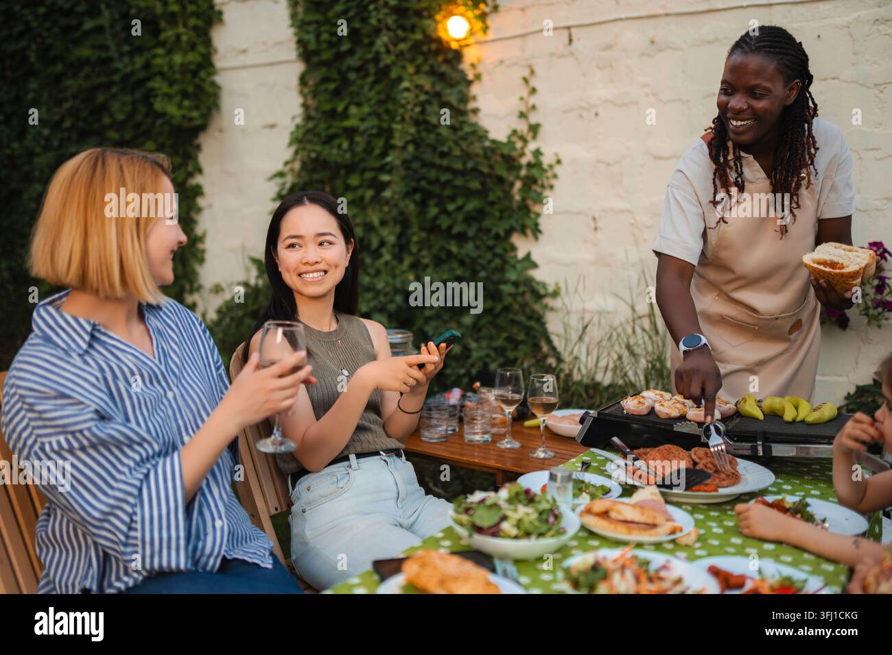 Freunde genießen ein Barbecue im Hinterhof, teilen Essen und Getränke Stockfoto