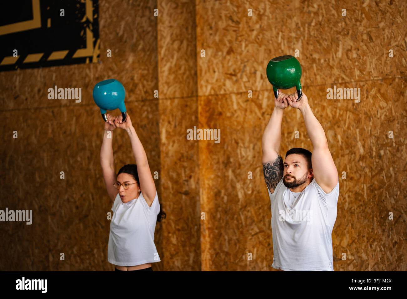 Menschen trainieren mit Kettlebells bei einem Überkopf-Workout Stockfoto