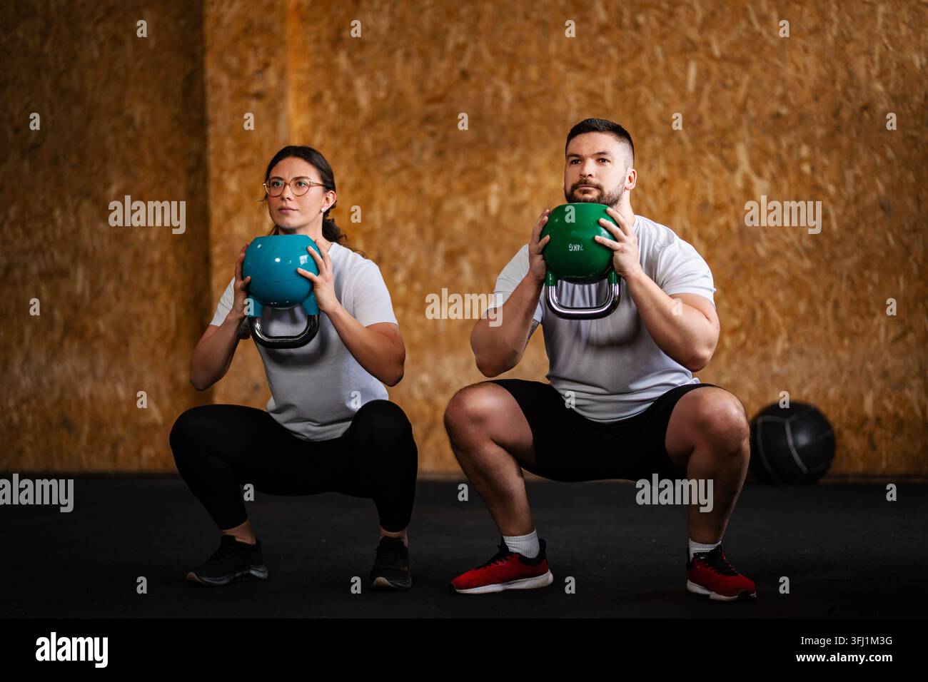 Paar macht Goblet Squats mit Kettlebells im Fitnessstudio Stockfoto