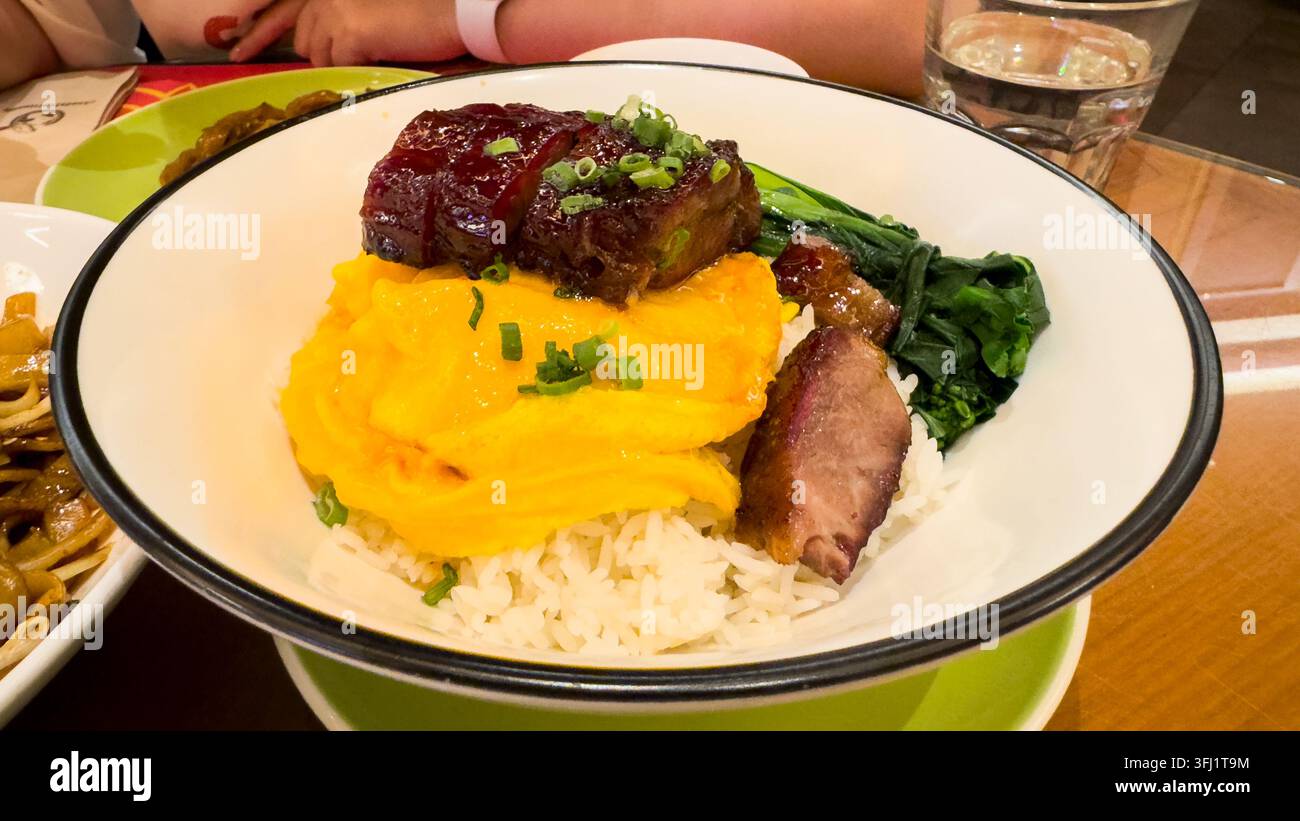 Reis, der mit Rührei, Char-Siu-Schweinefleisch und Gemüse garniert ist, serviert in einem kantonesischen Restaurant in Macau, China Stockfoto