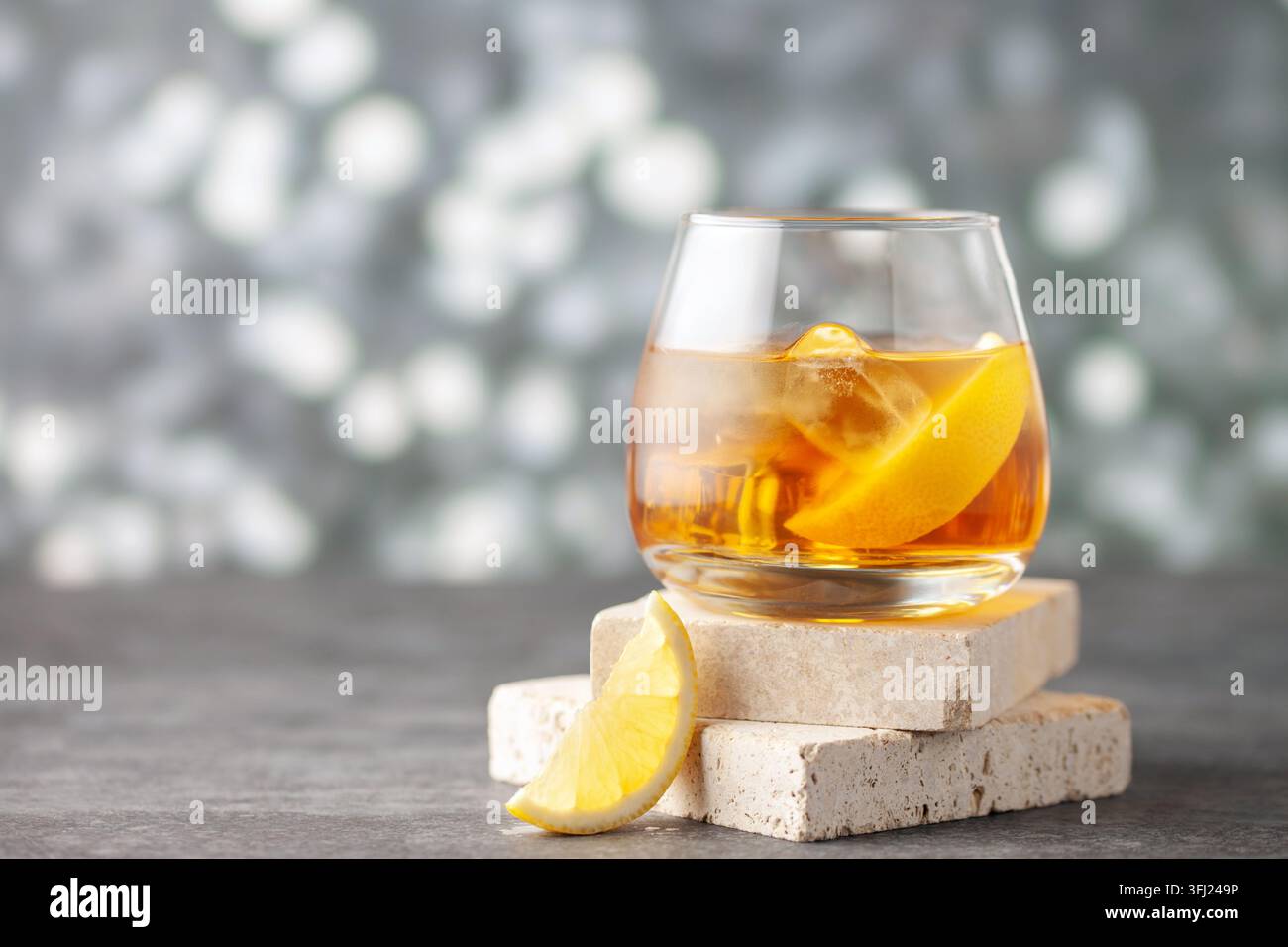 Glas Whiskey mit Zitrone und Eis auf Steinhintergrund. Stockfoto