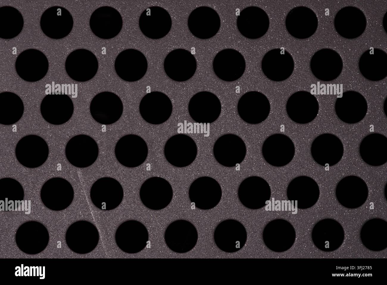 Geometrisches Muster aus gleichmäßig verteilten kreisförmigen Öffnungen in einer perforierten Metallplatte. Saubere industrielle Textur, geeignet für Design, Ingenieurwesen und Techno Stockfoto