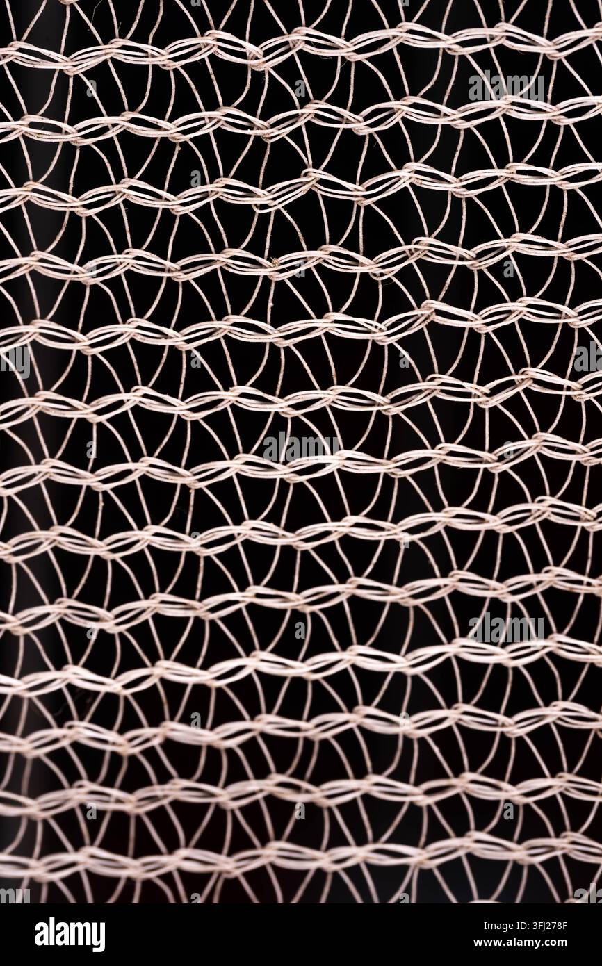Detaillierte Drahtgitterstruktur, isoliert vor schwarzem Hintergrund. Wiederholte Schlaufen und geometrische Formen erzeugen ein modernes abstraktes Muster. Stockfoto