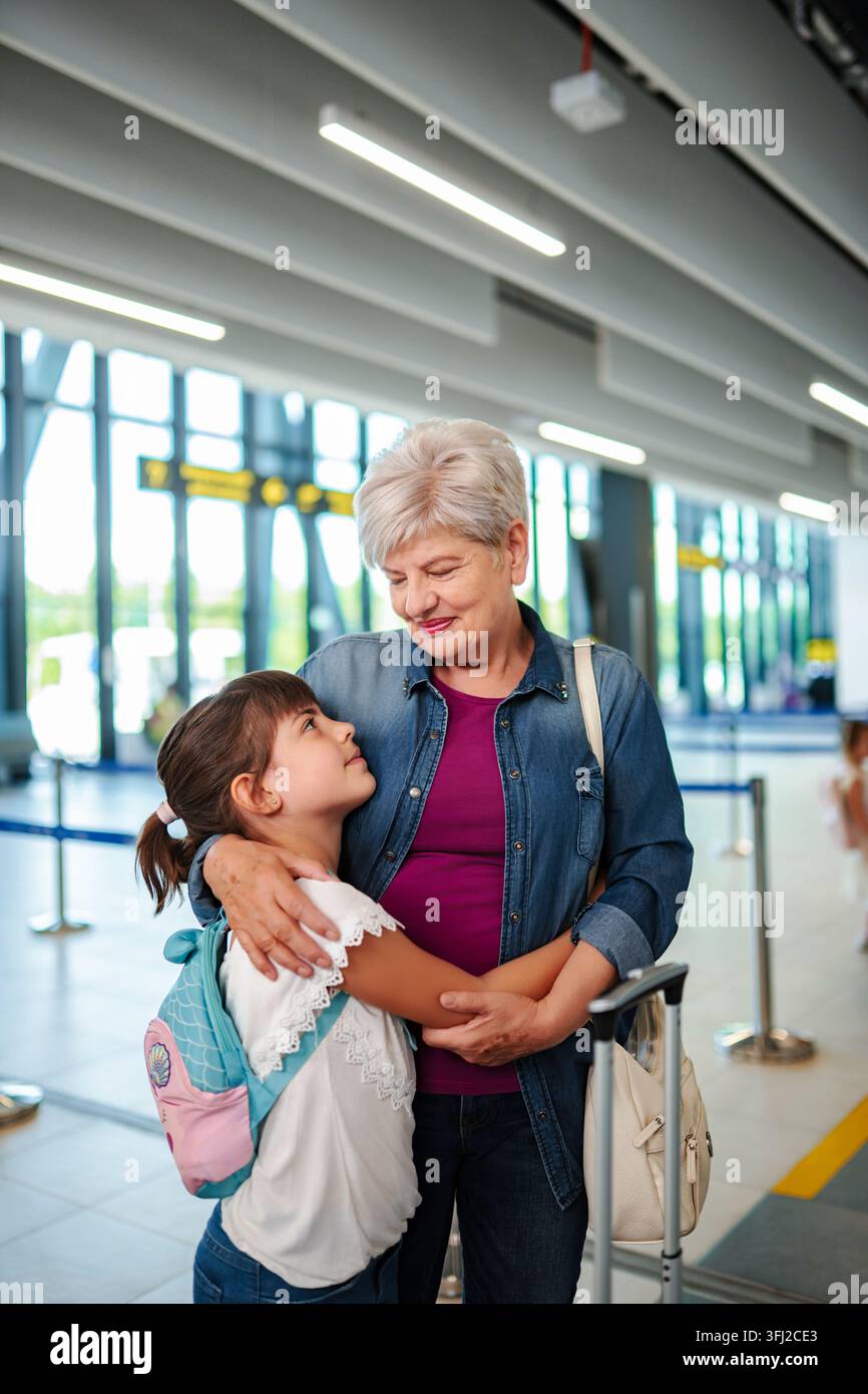 Großmutter und Mädchen umarmen sich im Flughafenterminal auf der Reise Stockfoto