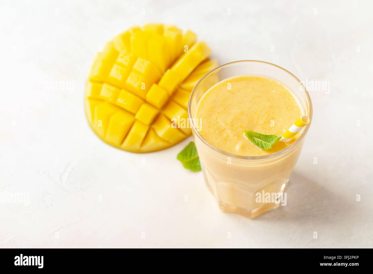 Smoothie oder Milchshake mit einer Mango in einem Glas auf dem Tisch. Diäternährung Stockfoto