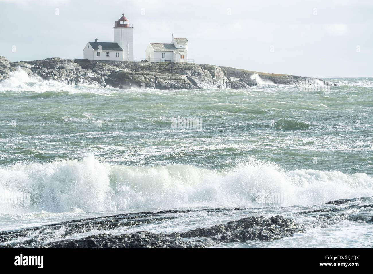 Wellen-Vordergrund-Perspektivschichten mit hellem brechendem Surf, rauem Wasser und entferntem Langoytangen-Leuchtturm in Norwegen für Küstenmaßstab, maritimes Wetter a Stockfoto