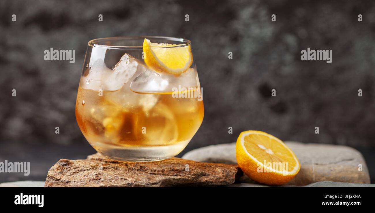Glas Whiskey mit Zitrone und Eis auf Steinhintergrund. Stockfoto