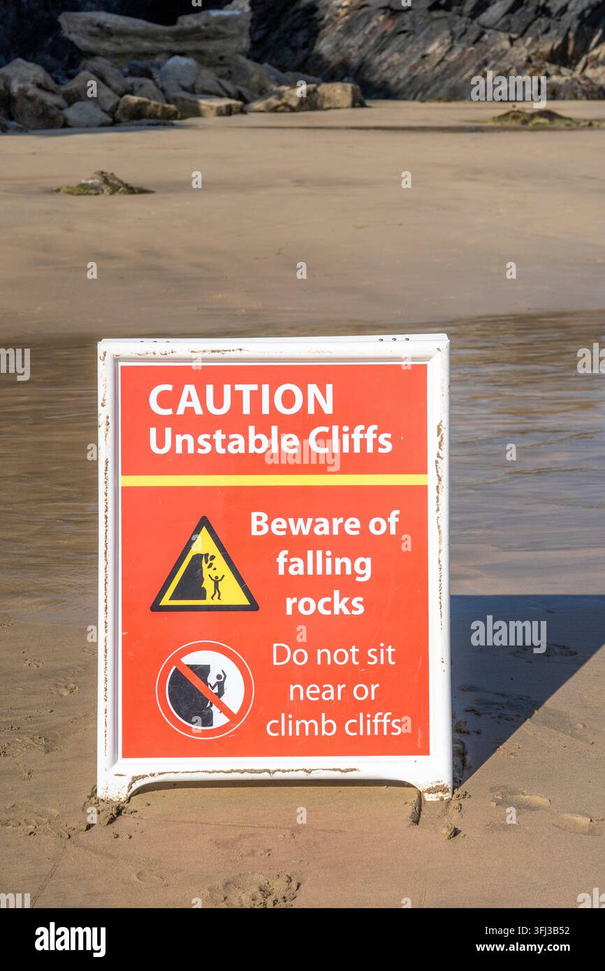 Schild warnt vor instabilen Klippen und fallenden Steinen an einem Strand Stockfoto