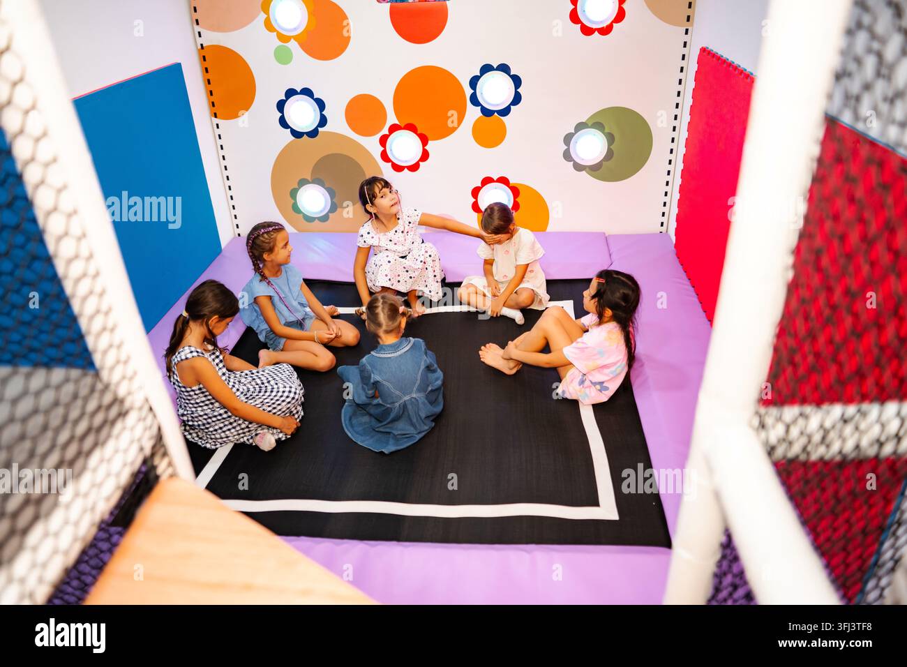Kinder, die auf einem Trampolin in einem Indoorgespielplatz Spiele spielen Stockfoto