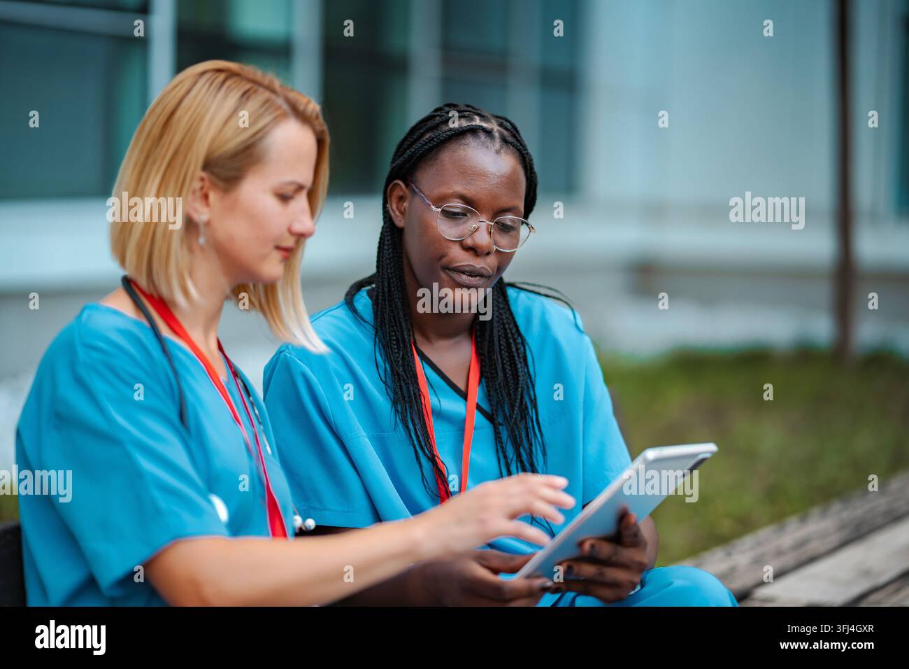 Zwei verschiedene Ärzte arbeiten gemeinsam an einem Tablet im Freien Stockfoto