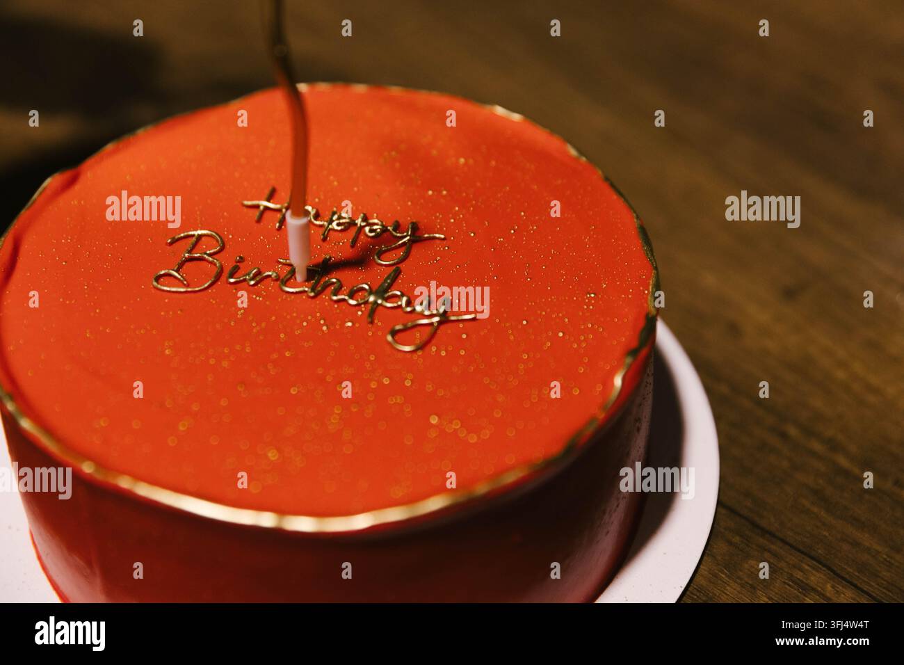 Eleganter runder roter Geburtstagskuchen mit goldener "Alles Gute zum Geburtstag"-Beschriftung und zarten goldenen Details. Festliches Dessert für Geburtstagsfeier und besonderen o Stockfoto