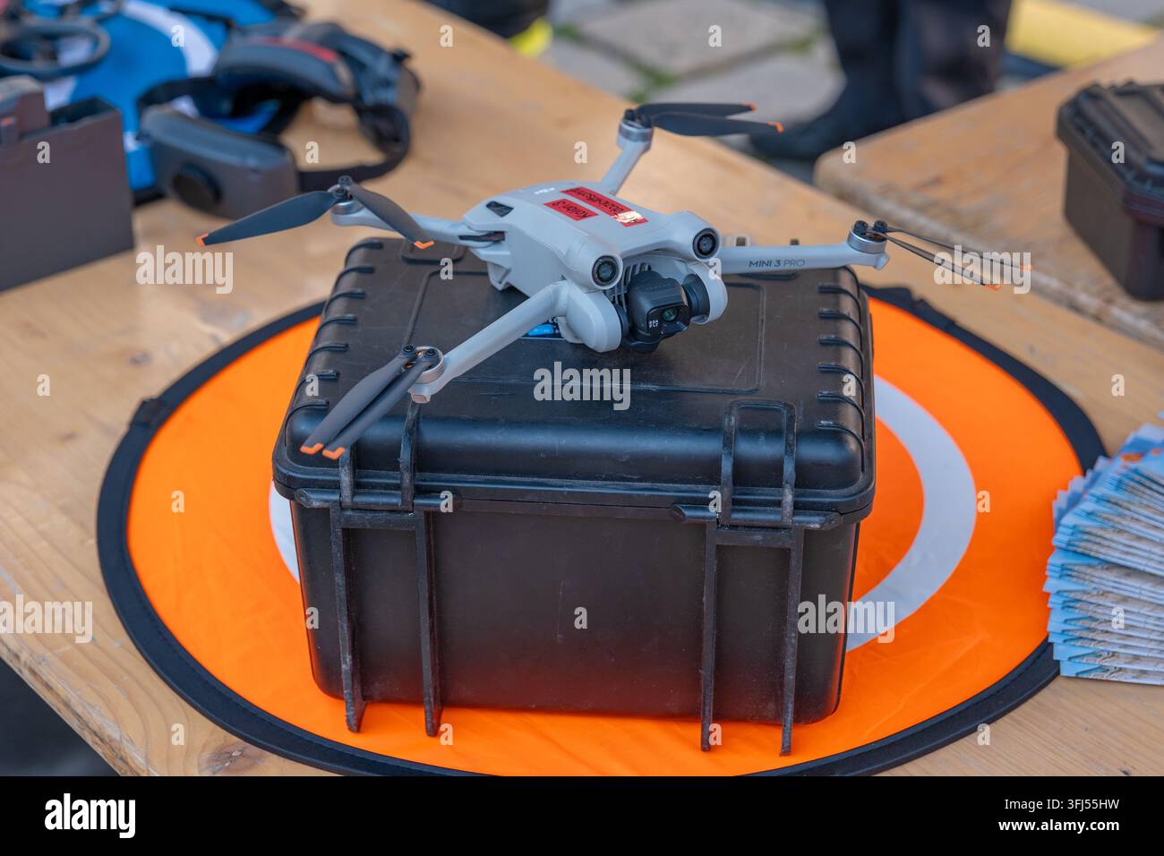 WIEN, ÖSTERREICH, 12. September 2026: Ein Mini 3 Pro-Drohne steht auf einem schwarzen Koffer über einer orangefarbenen Landeplattform. Stockfoto