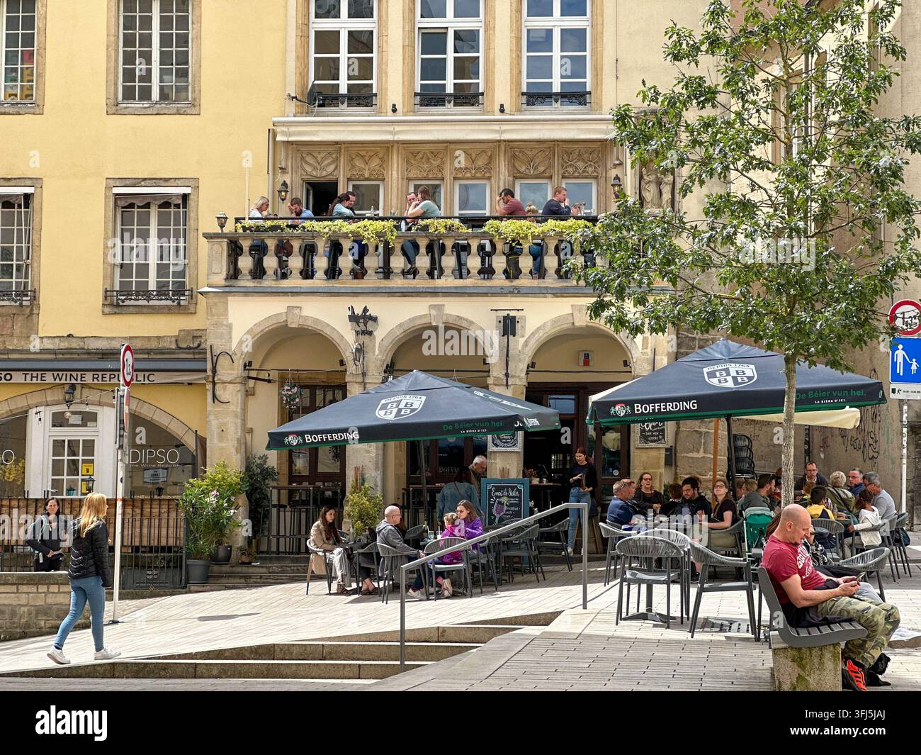 Historische europäische Café-Terrasse mit Sitzplätzen im Freien und Menschen. Historische europäische Café- und Restaurantterrasse mit Sitzplätzen im Freien unter einem Sonnenschirm - Smartphone-aufgenommenes Stockfoto