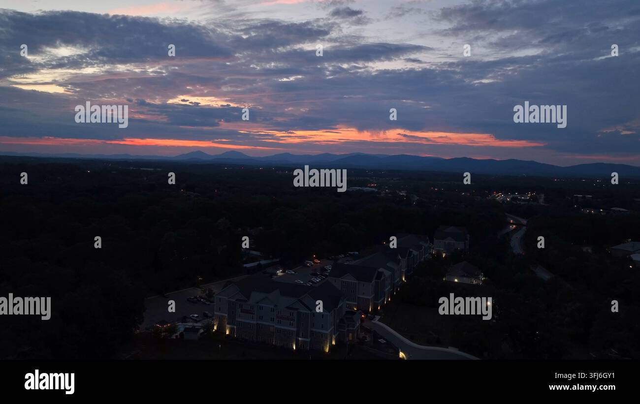 Luxuriöse Mehrfamilienwohnungen mit Gemeinschaftsbereich in einem Vorort einer amerikanischen Stadt. Dämmerungsszene nach Sonnenuntergang. Luftaufnahmen beim Abstieg. Mystische bedeckte Wolken am Himmel Stockfoto
