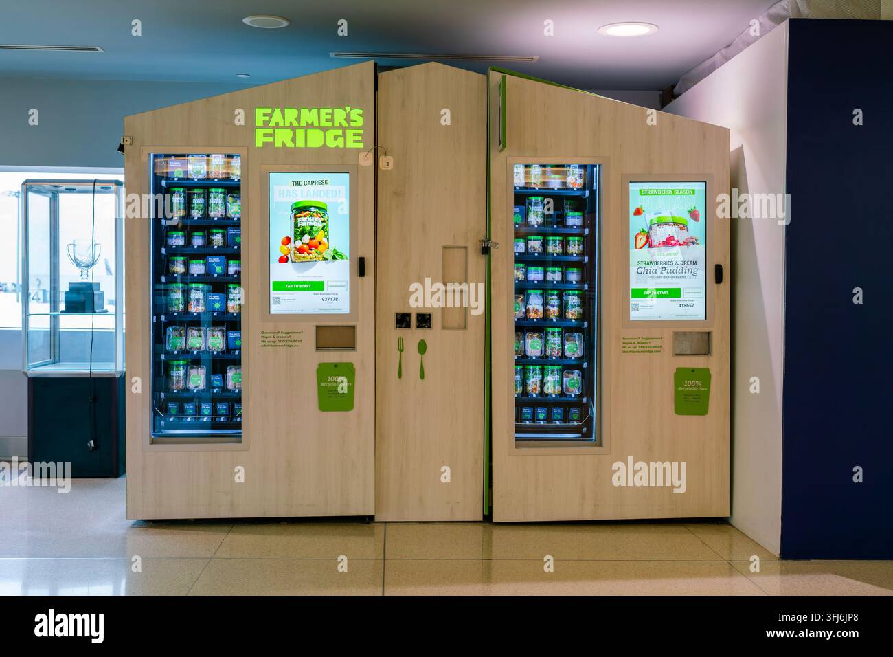 New York, USA - 18. Aug. 2026: Zwei holzverkleidete Farmer's Fridge Smart-Vending-Maschinen stehen nebeneinander im Bahnhofsbereich von Terminal 8 am John F. K Stockfoto