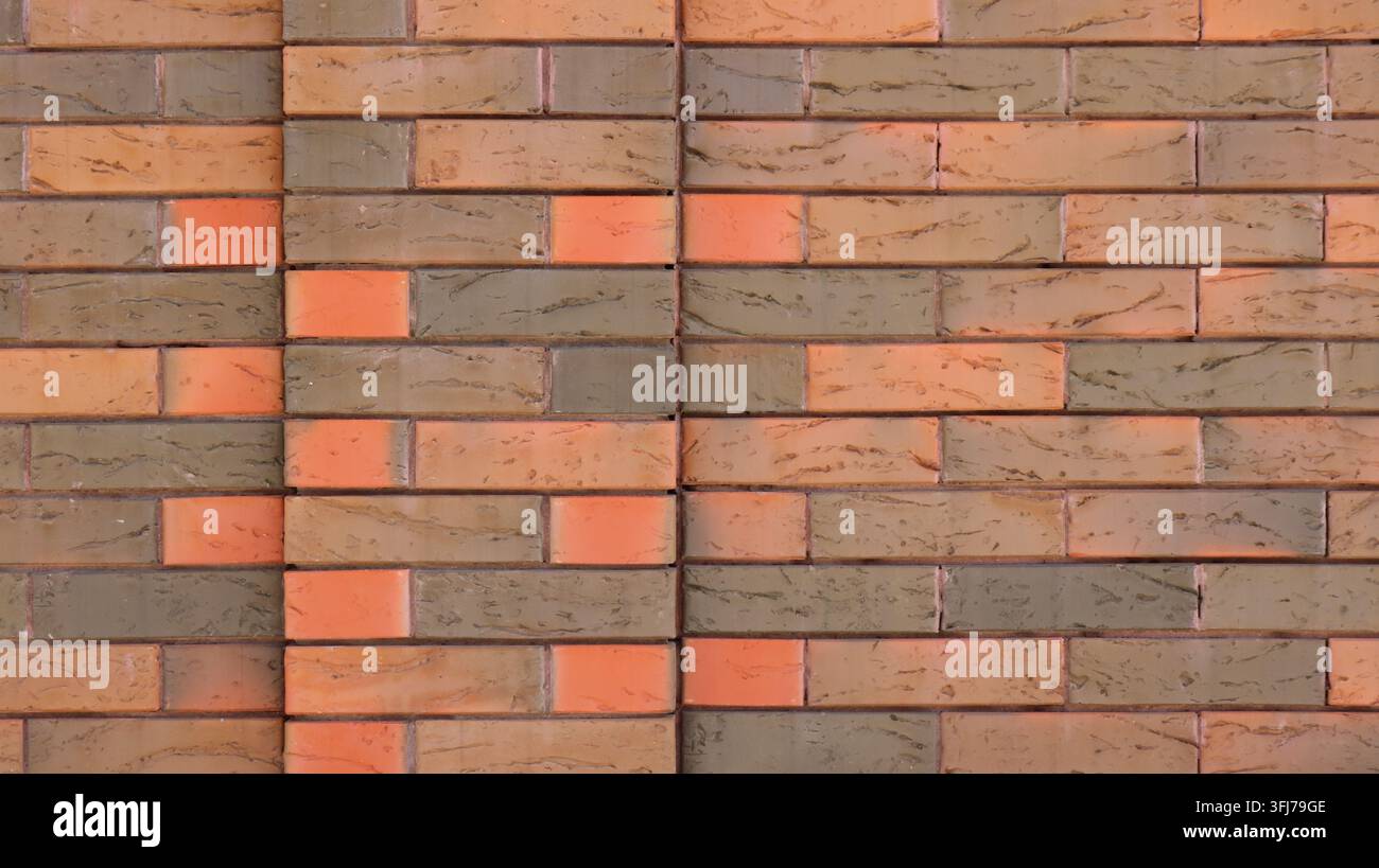 Ein Abschnitt moderner Ziegelfassaden mit einer gesprenkelten Textur. Die horizontalen Reihen bestehen aus Klinkerziegeln in Terrakotta-, Braun- und Orangetönen Stockfoto