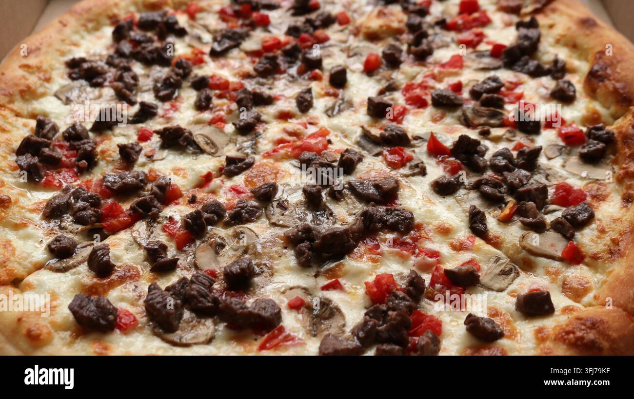 Eine appetitliche Pizza auf einem dicken, fluffigen Teig mit einem goldbraunen Finish. Sie ist großzügig mit geschmolzenem Käse und Stücken saftigen Fleisches belegt Stockfoto