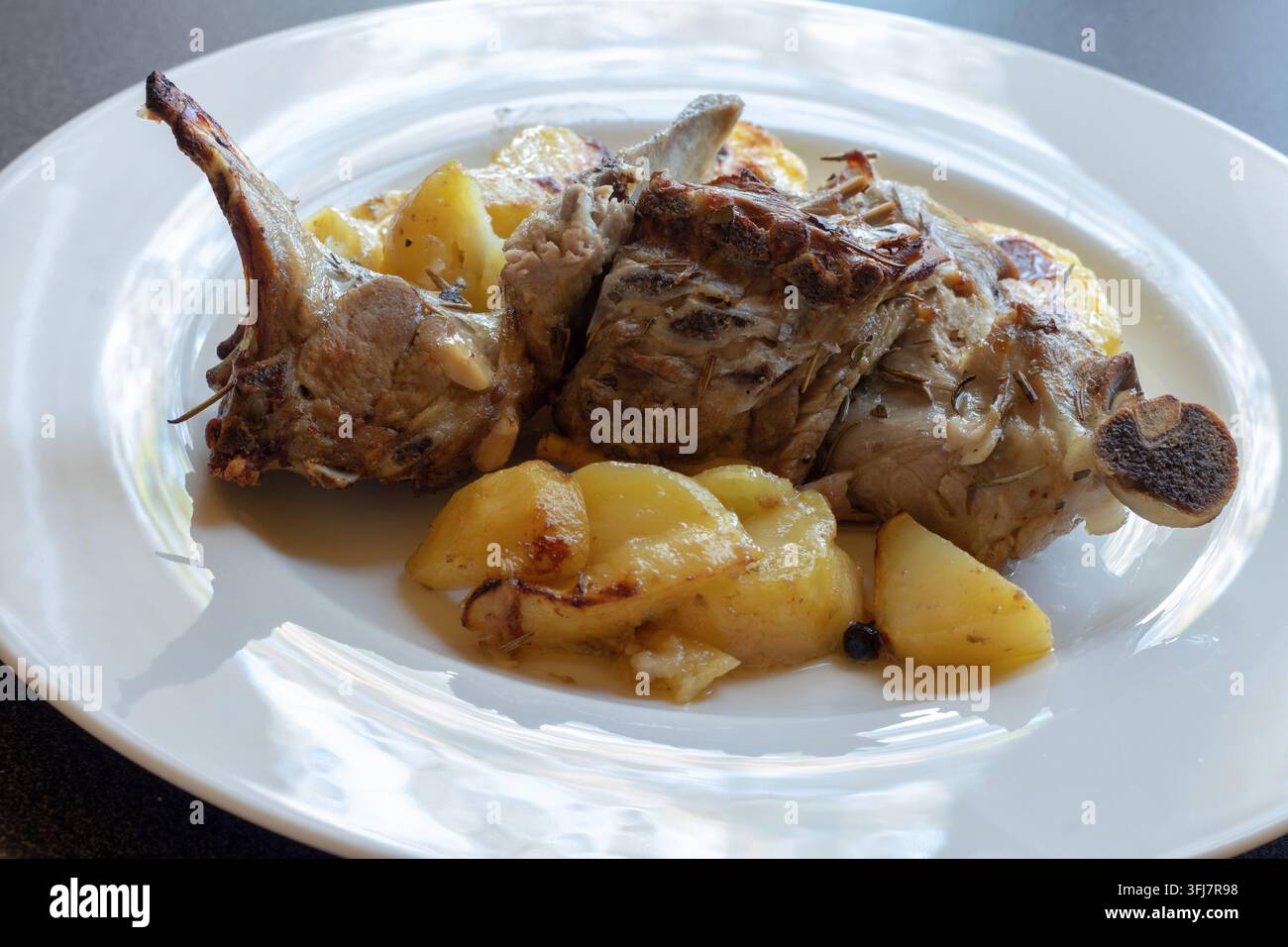 45-Grad-Ansicht von gebratenem Lammkarree mit goldenen Röstkartoffeln, ein traditionelles italienisches ofengebratenes Fleischgericht auf einem weißen Teller Stockfoto