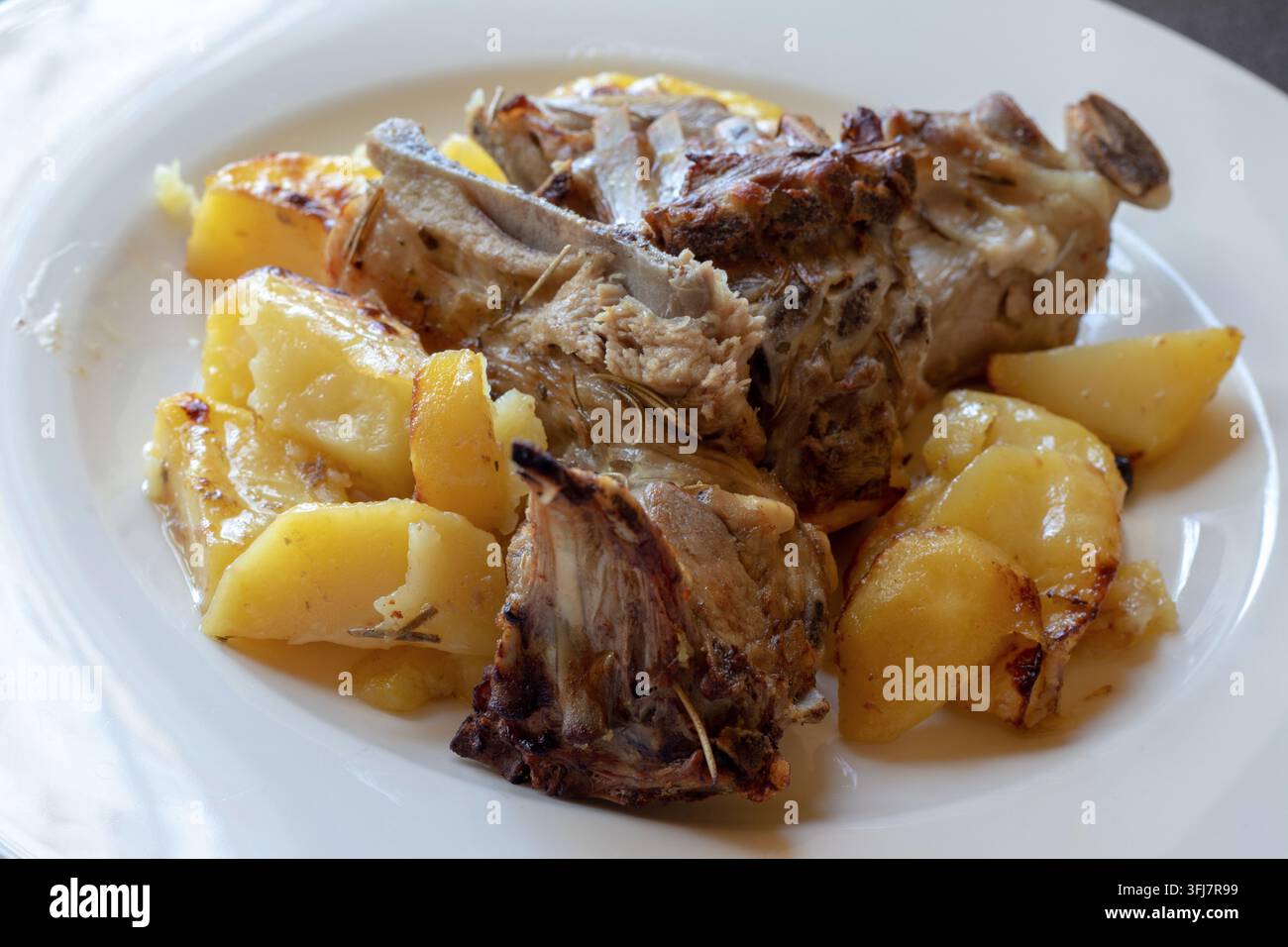 Nahaufnahme von gebratenem Lammkarré mit goldenen Röstkartoffeln, ein traditionelles italienisches Ofengeschirr mit Fleisch auf einem weißen Teller Stockfoto
