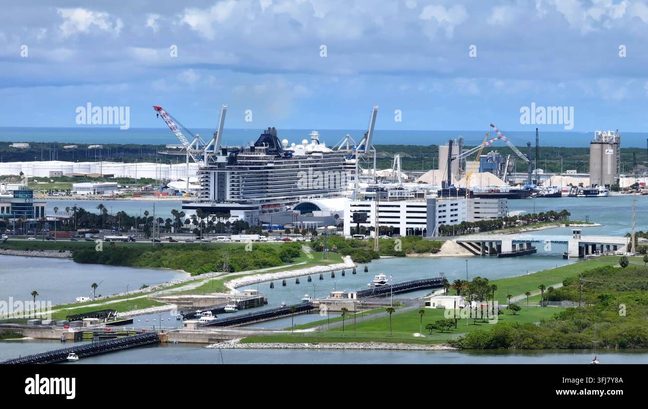 Riesenkreuzer im Hafen von Cape Canaveral City mit dem Ozean im Hintergrund. Industriekräne mit Schiffen am Dock. Luftbild, weitwinklig, Florida. Stockfoto