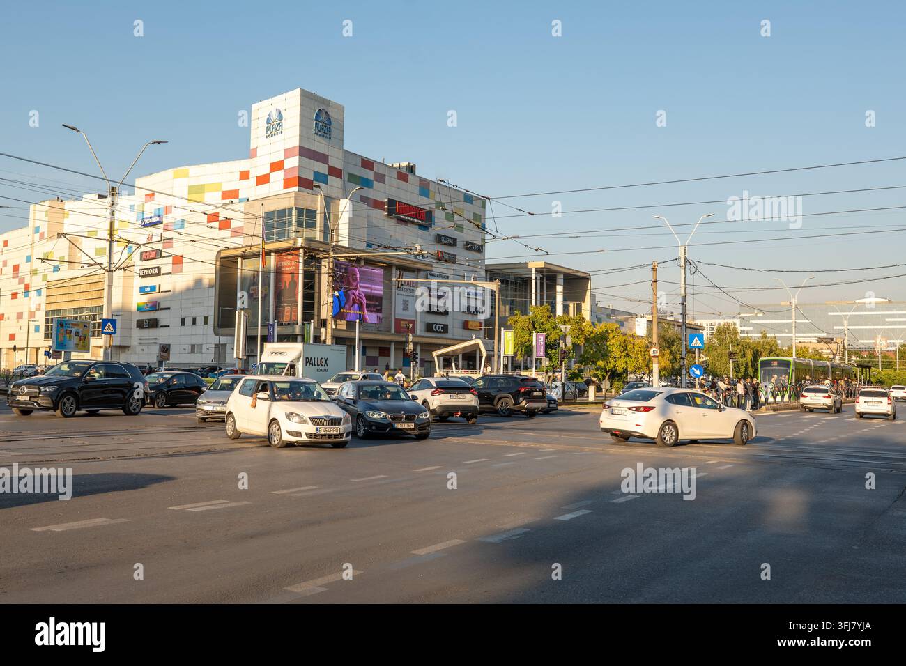 Fahrzeuge fahren durch eine belebte Straßenkreuzung in der Nähe der Fassade des Einkaufszentrums Plaza Romania im Stadtteil Bukarest, Rumänien Stockfoto