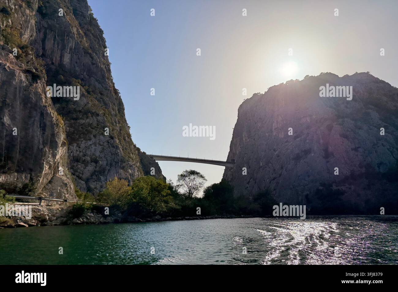 Sonne lugt hinter Klippen in der Cetina-Schlucht nahe Omiš an der dalmatinischen Küste, Kroatien. Mit moderner Straßenbrücke, die die Schlucht überspannt. - Smartphone-aufgenommenes Stockfoto