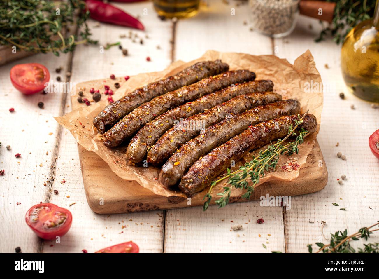 Gegrillte Würste auf Holzbrett mit Kräutern Stockfoto