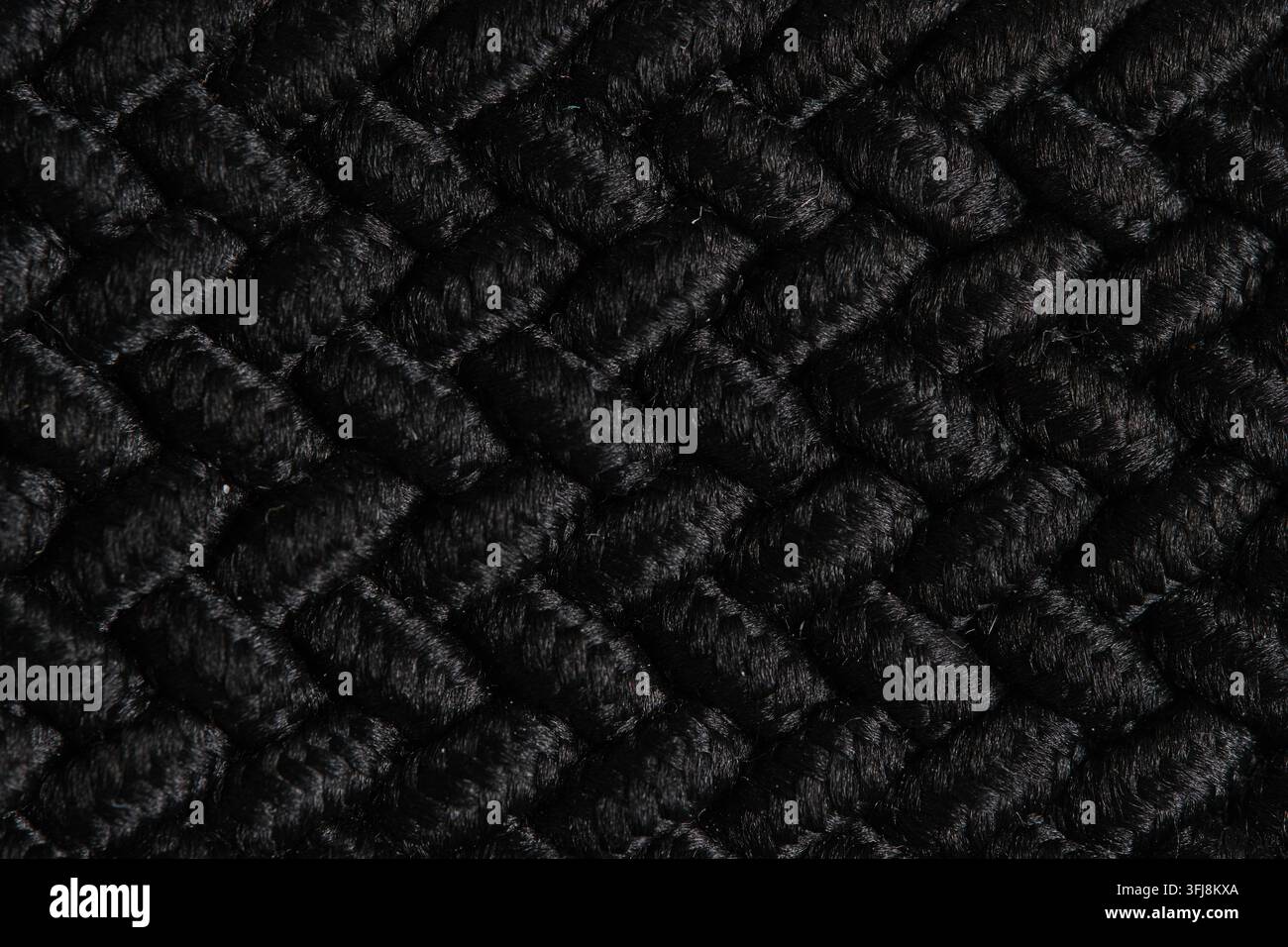Abstraktes schwarzes Strickstofftextilmuster mit dichter geometrischer gewebter Textur im Hintergrund Stockfoto