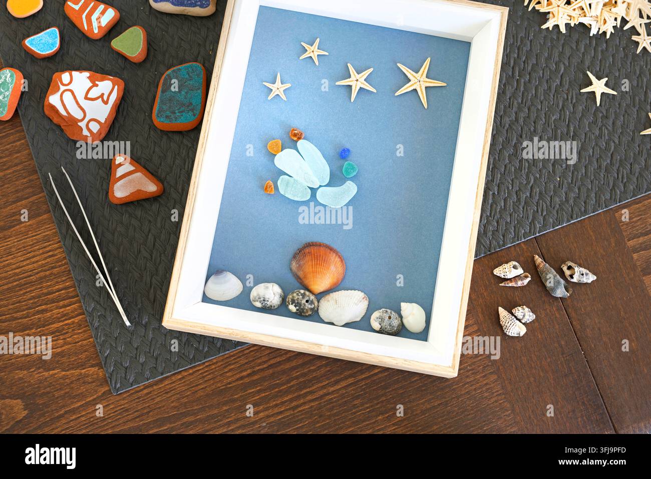 Aufbereitetes Meerglas-Schattenbox-Stranddekor-Basteln. Umweltfreundliche, nachhaltige Wohnkultur-Styling. Kreative Sommerhobby-DIY-Workshop-Hintergrund. Stockfoto
