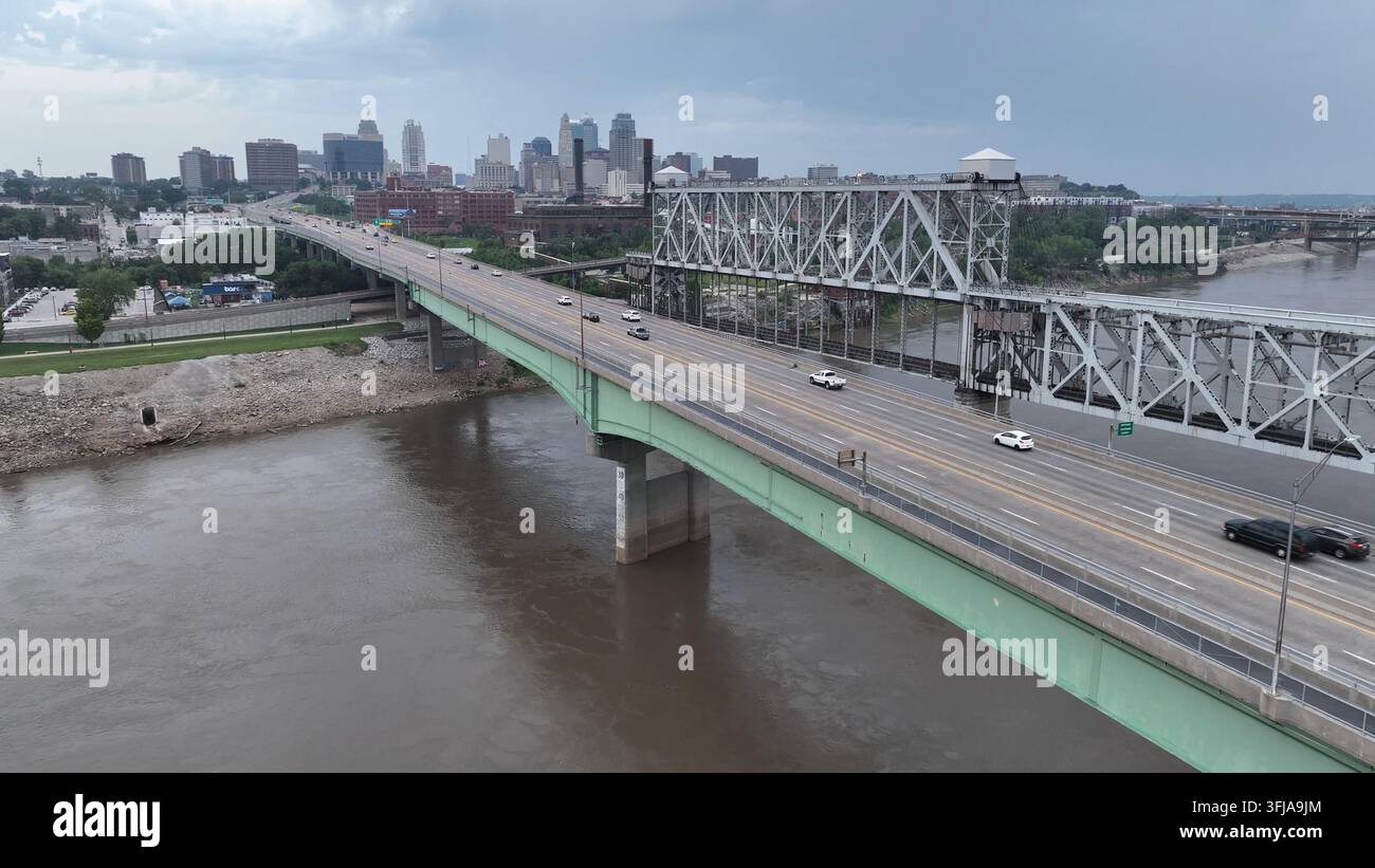 Kansas City an einem bewölkten Tag, wie vom Missouri-Fluss aus gesehen. Luftaufnahme, die den Verkehr auf der Brücke und die Skyline hinaufsteigt. Stockfoto