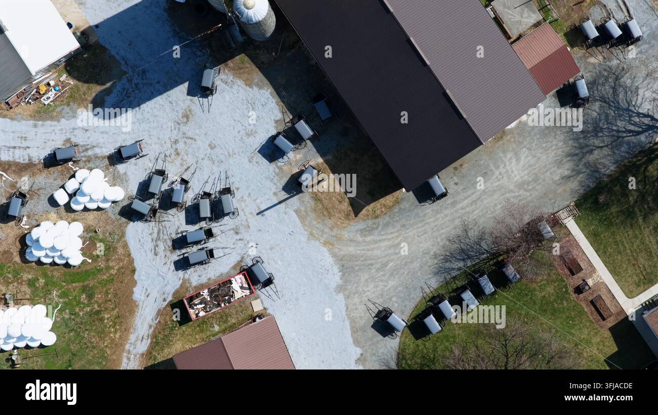 Luftbild von oben einer Amish-Farm in Pennsylvania, USA, pferdegezogene Kutschen, die in der Nähe von Scheunen und Silos geparkt sind, ländliche Landschaft mit traditionellem l Stockfoto